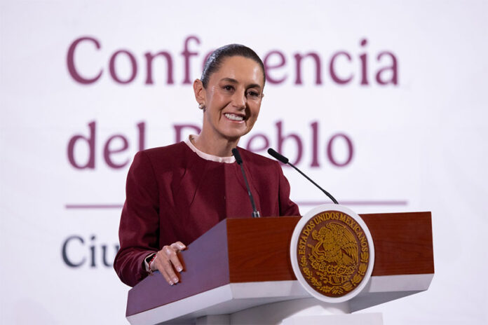 President Claudia Sheinbaum smiling as she stands at the presidential podium during a press conference discussing United States citizens arrested in Mexico