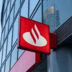 Sign with logo for Santander Bank, which has a red background and a stylized abstract image of a white swan. The sign is bolted toward the base of a skyscraper building.