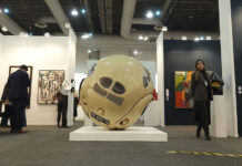 Spectators mill around an exhibition feature paintings and a large round sculpture at Zona Maco during Mexico City's Art Week 2025