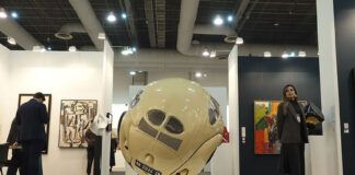 Spectators mill around an exhibition feature paintings and a large round sculpture at Zona Maco during Mexico City's Art Week 2025
