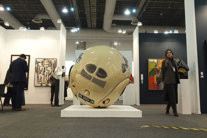 Spectators mill around an exhibition feature paintings and a large round sculpture at Zona Maco during Mexico City's Art Week 2025