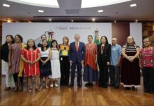 A group of Mexican politicians, administrators and academics stand in a group, several wearing clothing with traditional Indigenous designs