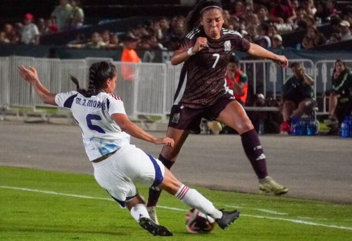 Two female soccer players wearing uniforms from different teams competing to take possession of the ball during a game