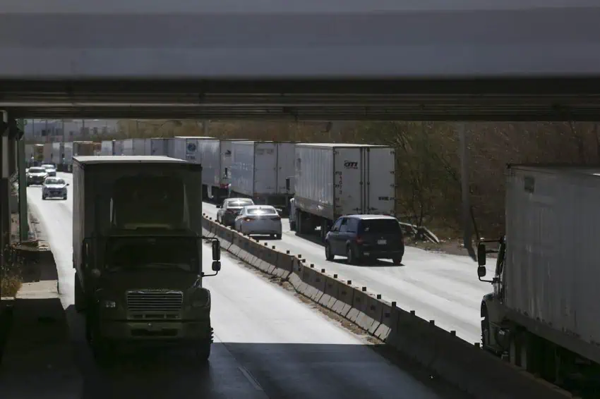 A stretch of Mexican highway with tractor trailer trucks and cars passing underneath an underpass on the Zaragoza-Ysleta international bridge in Ciudad Juárez.