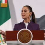 President Claudia Sheinbaum standing at the presidential podium during her daily press conference, speaking about tariffs on Mexican exports.