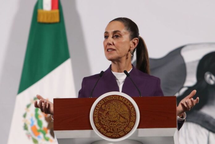 President Claudia Sheinbaum standing at the presidential podium during her daily press conference, speaking about tariffs on Mexican exports.