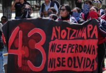 Protesters hold a large banner reading "43 Ayotzinapa, no se perdona, no se olvida"