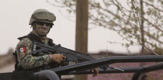 Mexican soldier in camouflage rests with gun