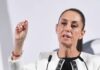 Mexico's President Claudia Sheinbaum standing at the presidential podium and gesturing with her thumb and forefinger as she makes a point during her daily press conference.