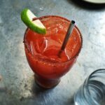 An irish michelada with lime, ice and a straw