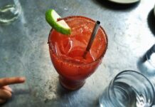 An irish michelada with lime, ice and a straw