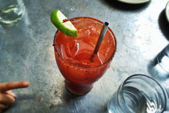 An irish michelada with lime, ice and a straw