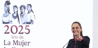 President Claudia Sheinbaum smiles and points at the camera from the podium of her morning press conference