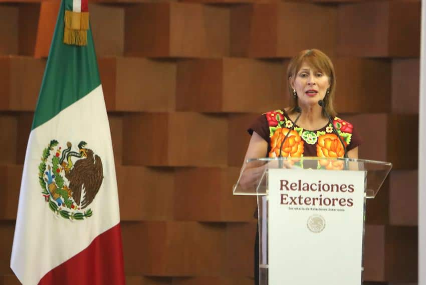 Tatiana Clouthier stands at a podium bearing the words "Relaciones Exteriores" next to a Mexican flag