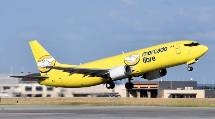 A yellow Mercado Libre airplane takes off from a runway