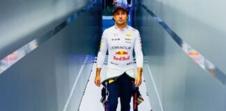 Checo Pérez walks down a hallway after returning from a race, wearing his Red Bull Formula 1 uniform