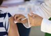 hands of medical personel giving a vaccination injection to a girl's bared arm