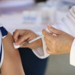 hands of medical personel giving a vaccination injection to a girl's bared arm