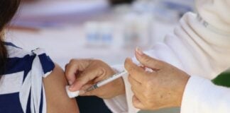 hands of medical personel giving a vaccination injection to a girl's bared arm