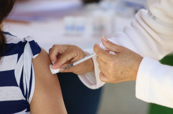 hands of medical personel giving a vaccination injection to a girl's bared arm