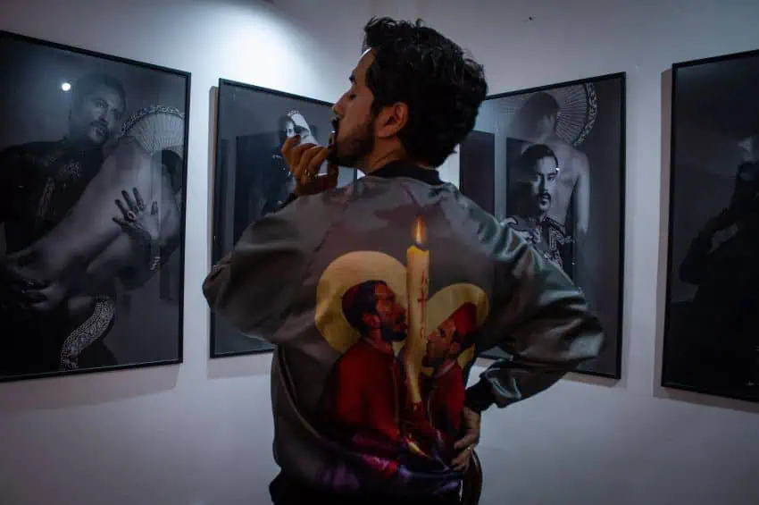 Artist Fabián Cháirez poses in a shirt featuring a painting of two priests licking a candle, from exhibition "The Coming of the Lord"