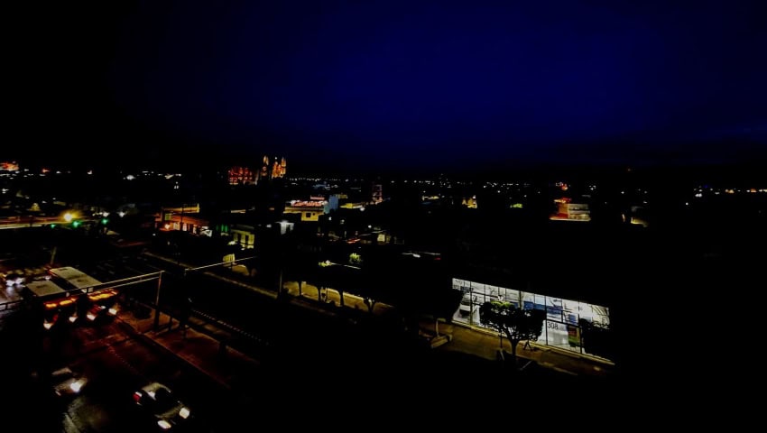 Street in Leon, Guanajuato, under blackout conditions, with the city skyline, mostly unlit, in the background.