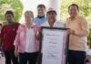 Mexico's Environment Minister, Alicia Barcena, a middle-aged woman with graying hair stands next to an unidentified Mexican man holding a framed enlarged document of certification of Sacpukenha as one of three new Maya protected areas. Around them are other people smiling into the camera.