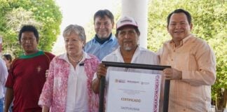 Mexico's Environment Minister, Alicia Barcena, a middle-aged woman with graying hair stands next to an unidentified Mexican man holding a framed enlarged document of certification of Sacpukenha as one of three new Maya protected areas. Around them are other people smiling into the camera.