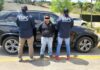 Two police officers with their backs to the camera standing in front of a police sedan. Their jackets say "SSPC Investigacion." Between them is a man facing the camera with his arms cuffed behind his back. His eyes are digitally covered with a black bar to hide his identity.