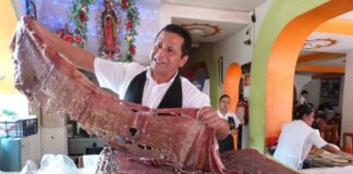 A man holds out a ribbon of cecina de yecapixtla