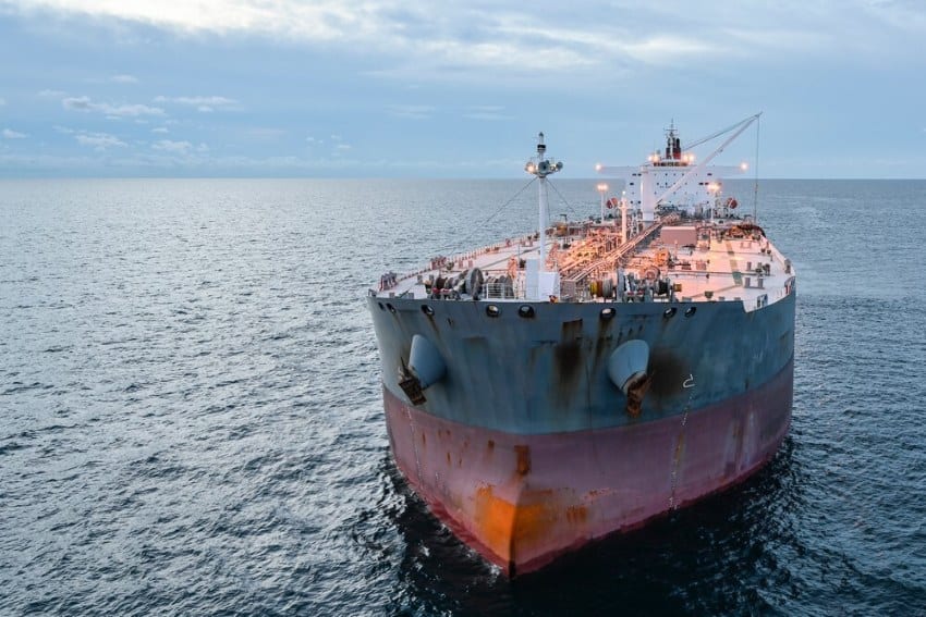 Crude oil tanker in the ocean. It is painted with a thick stripe of red on the bottom from side to side, and an equally thick strip of blue on the top half of the tanker.