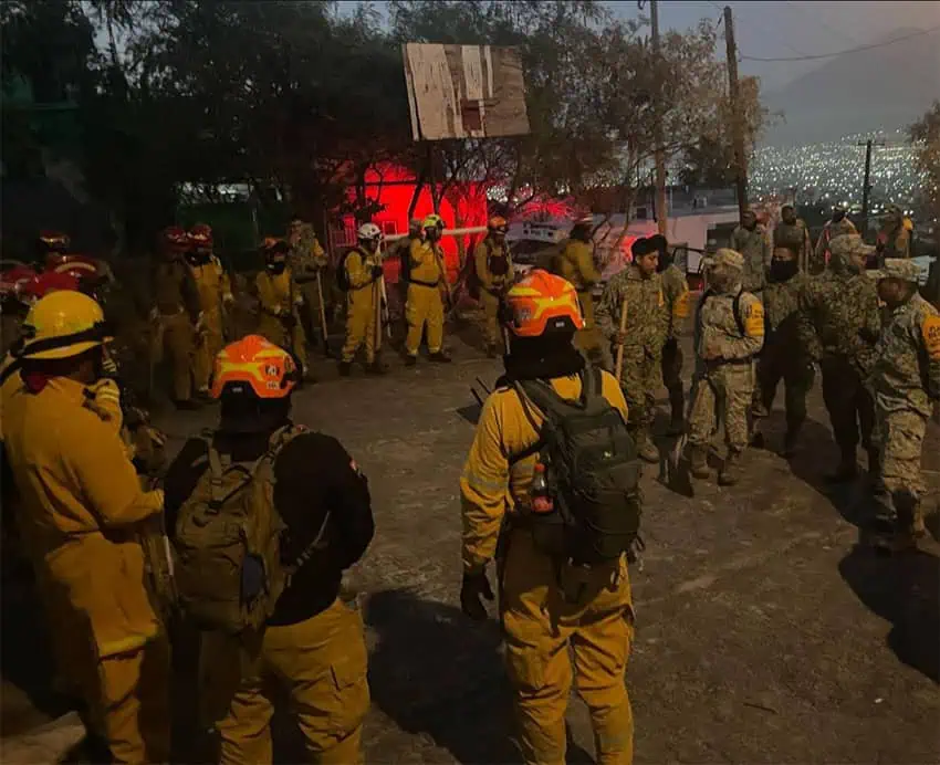 Firefighters gather on a hill with the city of Monterrey in the background