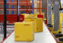 DHL boxes move down a conveyor belt in an industrial facility