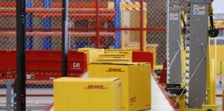 DHL boxes move down a conveyor belt in an industrial facility