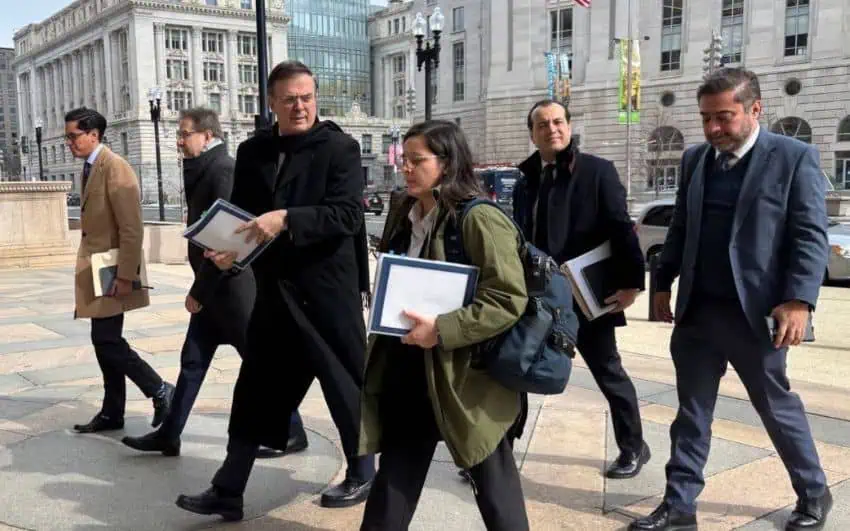 Un grupo de hombres y mujeres en ropa de negocios caminando juntos por las calles de la ciudad, con carteras y tres carpetas de anillos