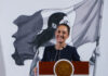 President Claudia Sheinbaum smiles from behind a podium at her morning press conference