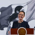 President Claudia Sheinbaum smiles from behind a podium at her morning press conference