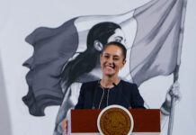 President Claudia Sheinbaum smiles from behind a podium at her morning press conference