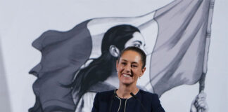 President Claudia Sheinbaum smiles from behind a podium at her morning press conference