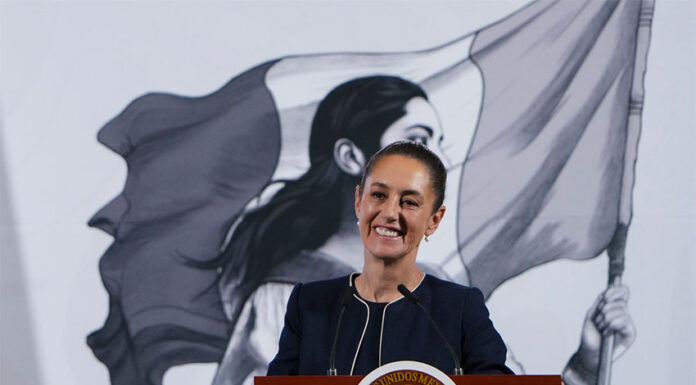 President Claudia Sheinbaum smiles from behind a podium at her morning press conference