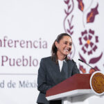 President Claudia Sheinbaum stands at a podium smiling