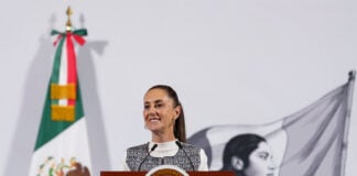 President Claudia Sheinbaum stands at a podium at her morning press conference