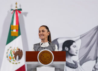 President Claudia Sheinbaum stands at a podium at her morning press conference