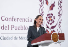 President Claudia Sheinbaum stands at a podium smiling