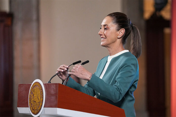 President Claudia Sheinbaum adjusts the microphone as she stands at a podium during her mañanera conference, where she discussed the hacking of her phone