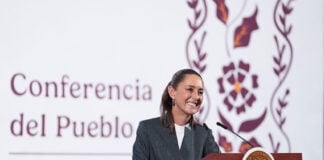 President Claudia Sheinbaum stands at a podium smiling