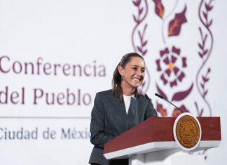 President Claudia Sheinbaum stands at a podium smiling