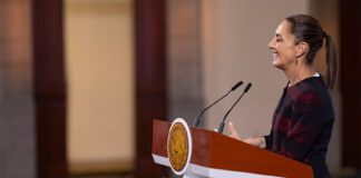 President Claudia Sheinbaum stands at a podium during her morning press conference