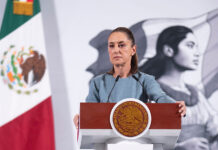 President Sheinbaum, looking serious, stands at the podium of her morning press briefing, where she cast doubt on some previous findings in the Teuchitlán extermination camp case