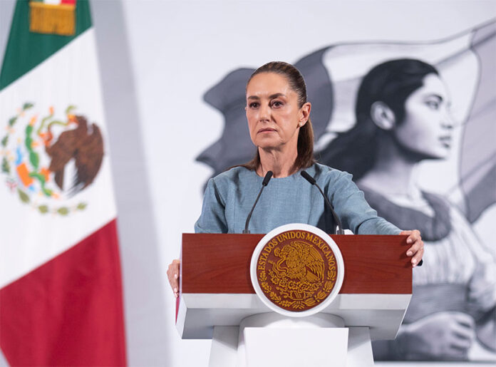 President Sheinbaum, looking serious, stands at the podium of her morning press briefing, where she cast doubt on some previous findings in the Teuchitlán extermination camp case